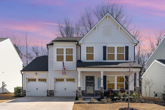 view of front of house featuring roof with shingles, covered porch, concrete driveway, board and batten siding, and stone siding