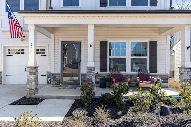 doorway to property with a garage, stone siding, a porch, and board and batten siding