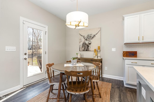 dining space featuring a notable chandelier, baseboards, and dark wood-style flooring