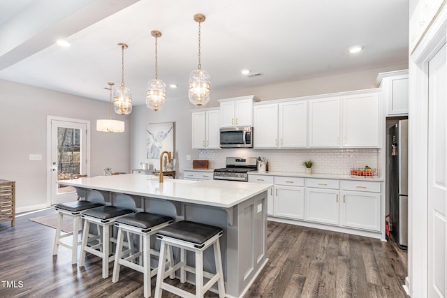 kitchen with pendant lighting, light countertops, stainless steel appliances, and white cabinets