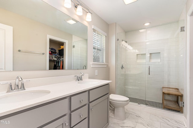 full bathroom with marble finish floor, a shower stall, a walk in closet, and a sink