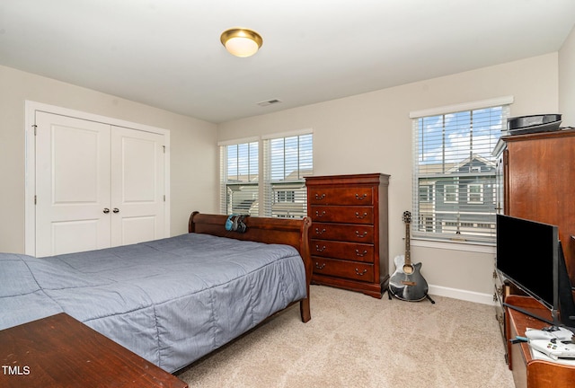 bedroom featuring baseboards, visible vents, a closet, and light colored carpet