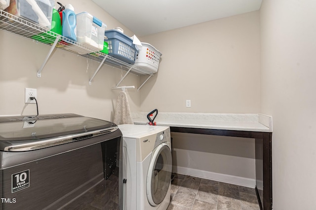 clothes washing area with washing machine and dryer, laundry area, and baseboards