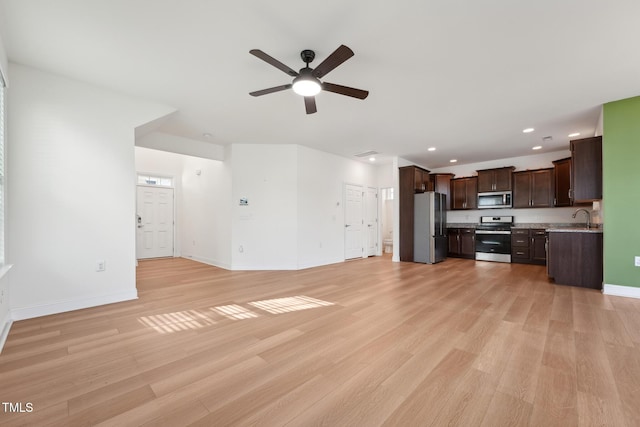 unfurnished living room featuring ceiling fan, recessed lighting, a sink, baseboards, and light wood finished floors