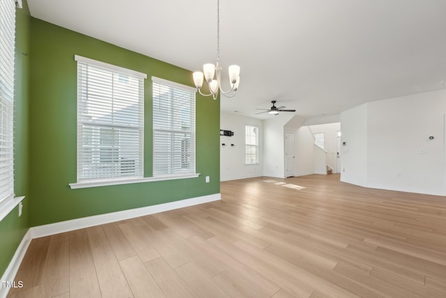 interior space featuring baseboards, light wood finished floors, and ceiling fan with notable chandelier