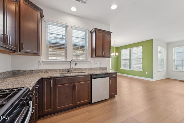 kitchen with pendant lighting, light wood-style flooring, stainless steel dishwasher, a sink, and light stone countertops