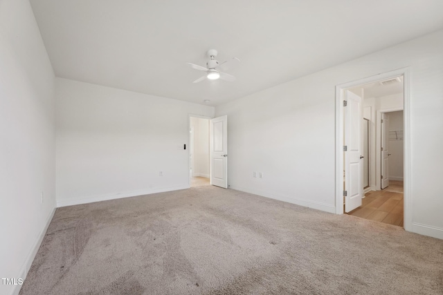 empty room with ceiling fan, visible vents, baseboards, and light colored carpet