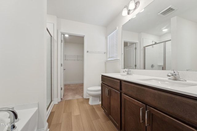 bathroom with wood finished floors, a sink, visible vents, and a walk in closet