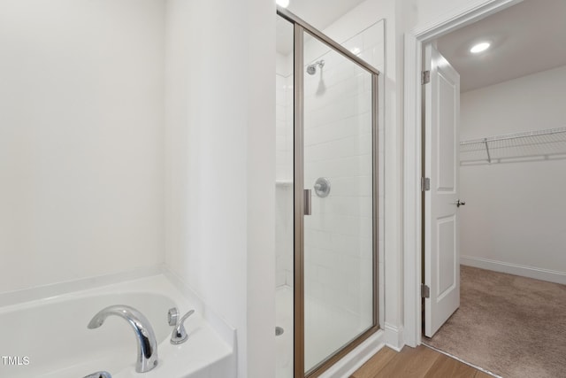 full bath featuring a garden tub, a shower stall, a spacious closet, and baseboards