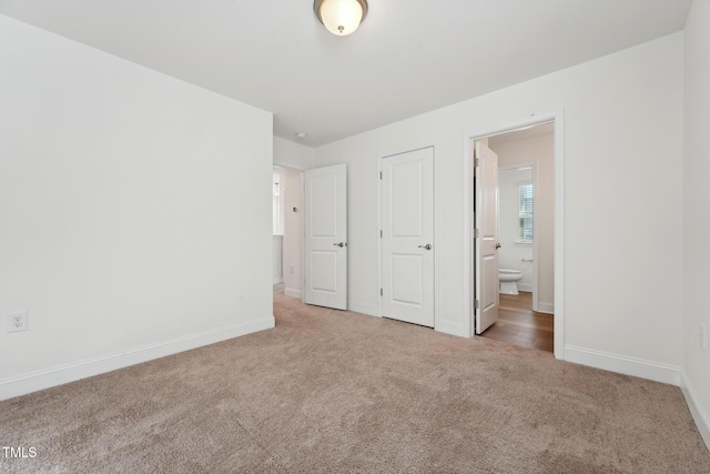 unfurnished bedroom featuring ensuite bath, baseboards, and carpet flooring