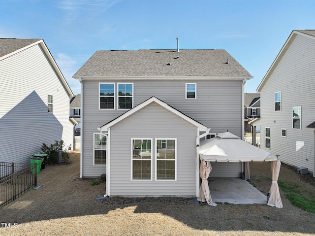 back of property featuring a shingled roof, a patio area, fence, and a gazebo