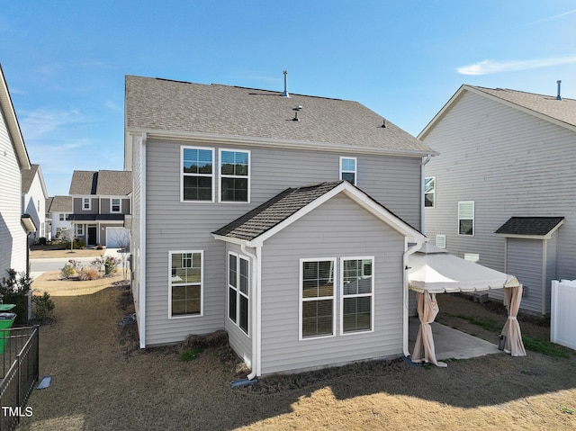 rear view of house featuring a patio area, roof with shingles, fence, and a gazebo