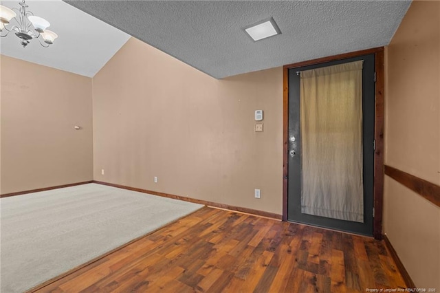 empty room with a notable chandelier, dark hardwood / wood-style floors, and a textured ceiling