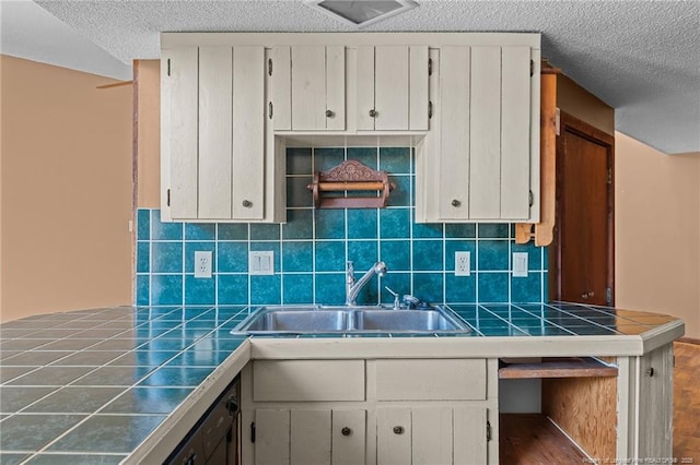 kitchen with white cabinetry, sink, tile counters, and backsplash