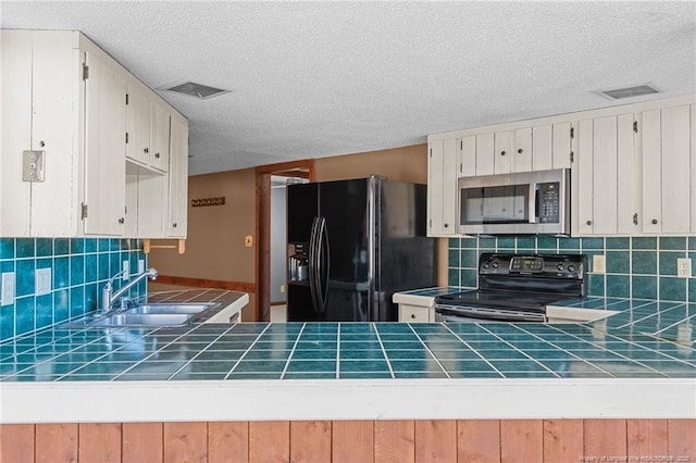 kitchen with range with electric cooktop, sink, tile counters, and black refrigerator with ice dispenser