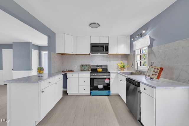 98 S Denise Ave, Coats, NC 27521 - kitchen featuring white cabinetry, kitchen peninsula, stainless steel appliances, light hardwood / wood-style flooring, and sink