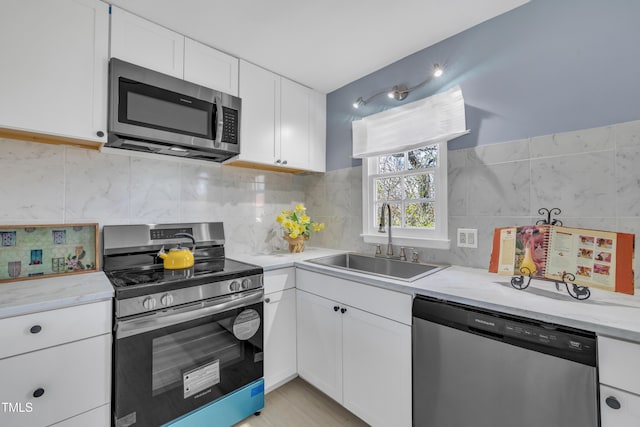 kitchen featuring sink, appliances with stainless steel finishes, white cabinetry, and tasteful backsplash