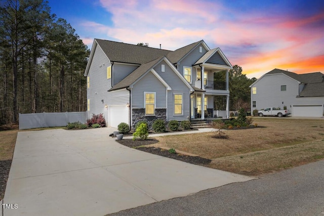 220 Green Haven Blvd, Youngsville, NC 27596 - view of front facade featuring covered porch, stone siding, fence, an attached garage, and a balcony
