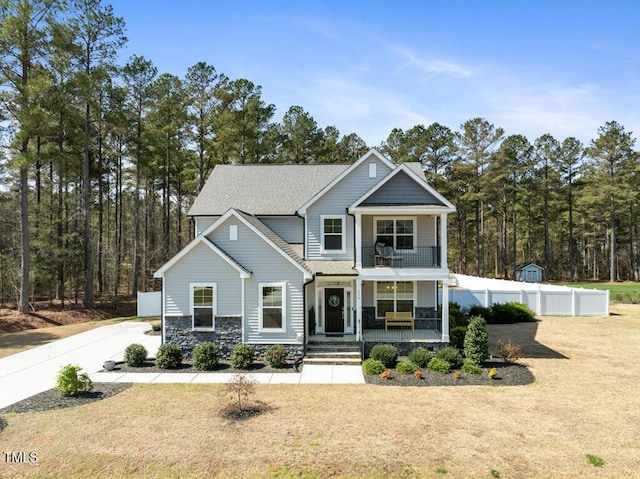 220 Green Haven Blvd, Youngsville, NC 27596 - view of front of property with a front yard, covered porch, stone siding, fence, and a balcony