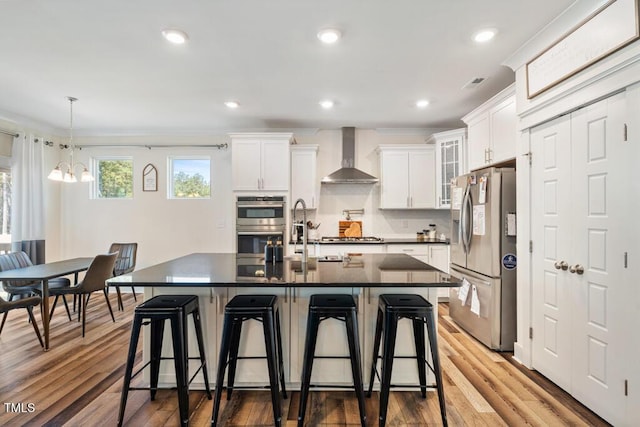 220 Green Haven Blvd, Youngsville, NC 27596 - kitchen featuring a breakfast bar area, wood finished floors, stainless steel appliances, wall chimney range hood, and dark countertops