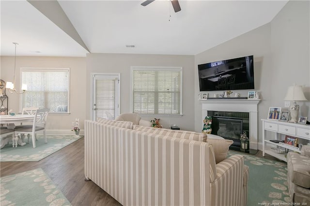 living room featuring lofted ceiling, ceiling fan with notable chandelier, and wood-type flooring