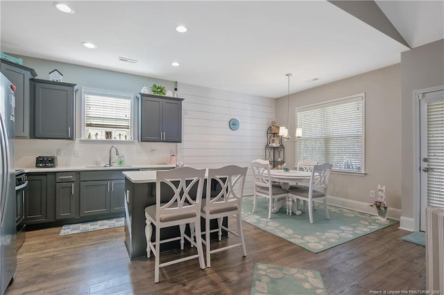 kitchen featuring sink, hanging light fixtures, a center island, a kitchen bar, and dark hardwood / wood-style flooring