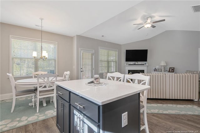 kitchen featuring hanging light fixtures, a kitchen breakfast bar, dark hardwood / wood-style floors, a kitchen island, and vaulted ceiling