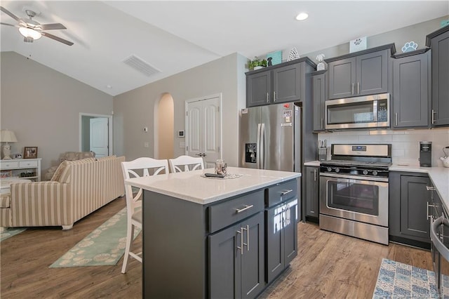 kitchen with stainless steel appliances, a center island, a kitchen breakfast bar, and gray cabinets