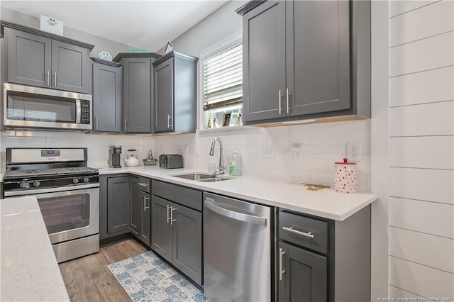 kitchen featuring stainless steel appliances, sink, light hardwood / wood-style flooring, and gray cabinetry