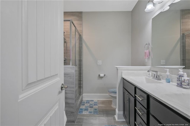 bathroom featuring vanity, a shower with shower door, and toilet