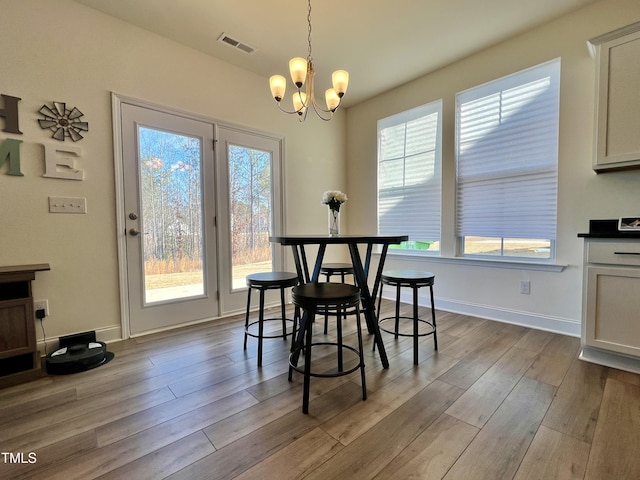 dining room with a healthy amount of sunlight, an inviting chandelier, and light hardwood / wood-style floors