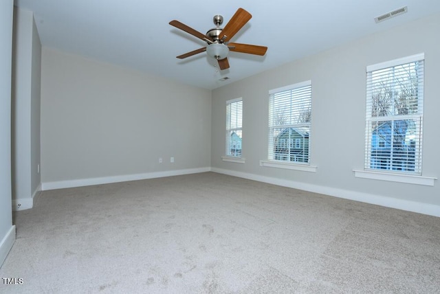 carpeted spare room featuring a ceiling fan, visible vents, and baseboards