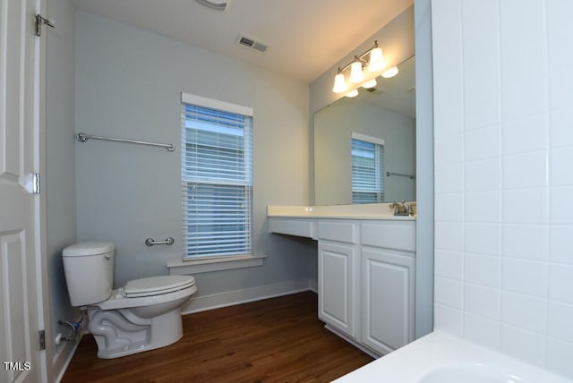 full bath featuring a tub to relax in, baseboards, visible vents, toilet, and wood finished floors