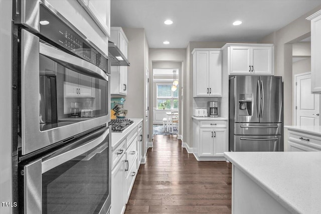 208 Cecelia Ct, Cary, NC 27519 - kitchen featuring stainless steel appliances, light countertops, extractor fan, dark wood-type flooring, and white cabinets
