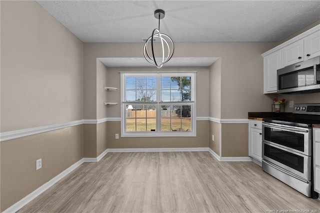 kitchen featuring white cabinetry, a textured ceiling, light hardwood / wood-style flooring, pendant lighting, and stainless steel appliances