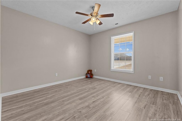 spare room with ceiling fan, a textured ceiling, and light wood-type flooring