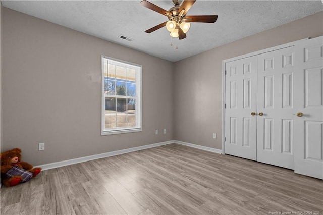 unfurnished bedroom with a closet, ceiling fan, a textured ceiling, and light hardwood / wood-style flooring