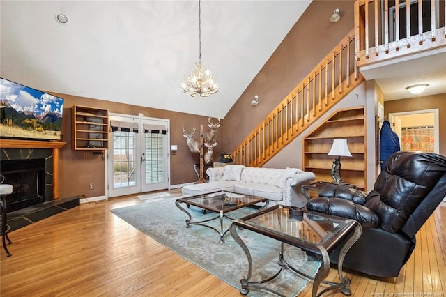 living room featuring french doors, high vaulted ceiling, wood-type flooring, and an inviting chandelier