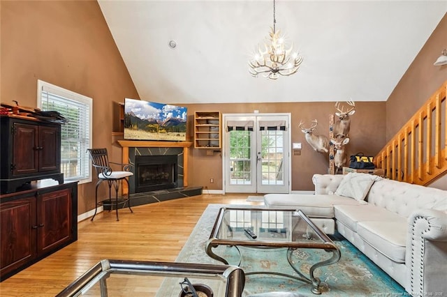 living room featuring built in shelves, high vaulted ceiling, light hardwood / wood-style flooring, a notable chandelier, and a fireplace