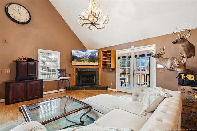 living room featuring french doors, high vaulted ceiling, a notable chandelier, a fireplace, and hardwood / wood-style floors