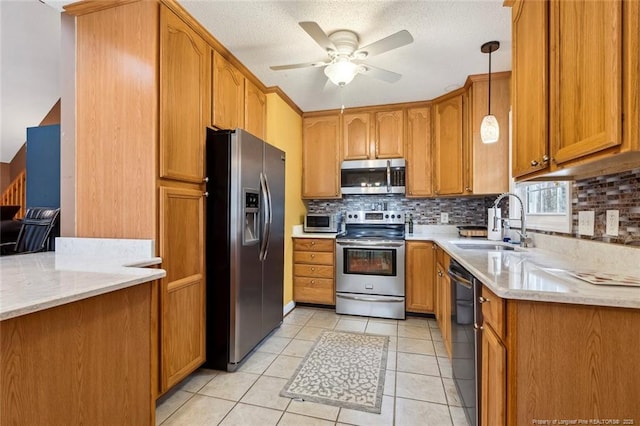 kitchen with appliances with stainless steel finishes, tasteful backsplash, sink, hanging light fixtures, and light tile patterned floors