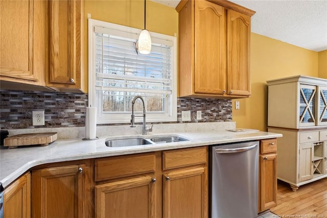 kitchen featuring sink, decorative light fixtures, stainless steel dishwasher, light hardwood / wood-style floors, and backsplash