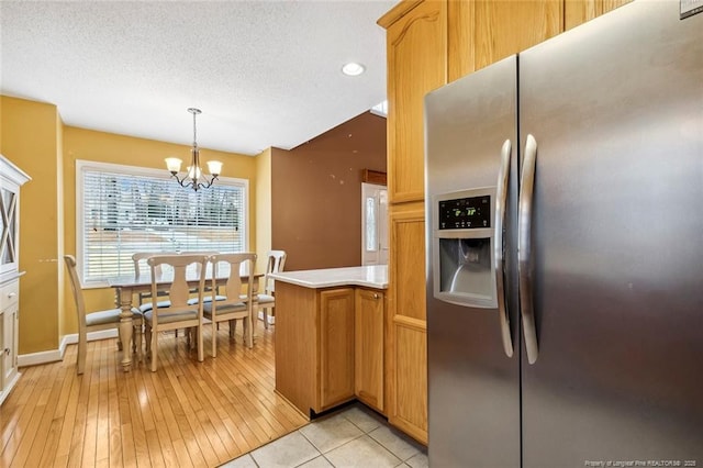 kitchen featuring an inviting chandelier, decorative light fixtures, stainless steel fridge, kitchen peninsula, and a textured ceiling