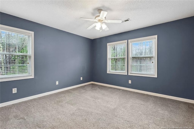 empty room with ceiling fan, carpet flooring, a textured ceiling, and a wealth of natural light