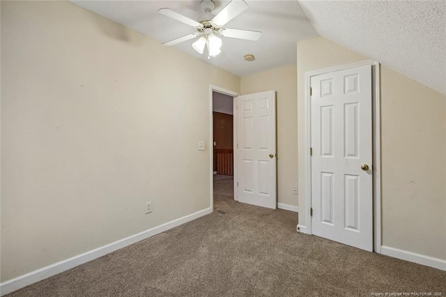 unfurnished bedroom featuring ceiling fan, carpet floors, a textured ceiling, and vaulted ceiling