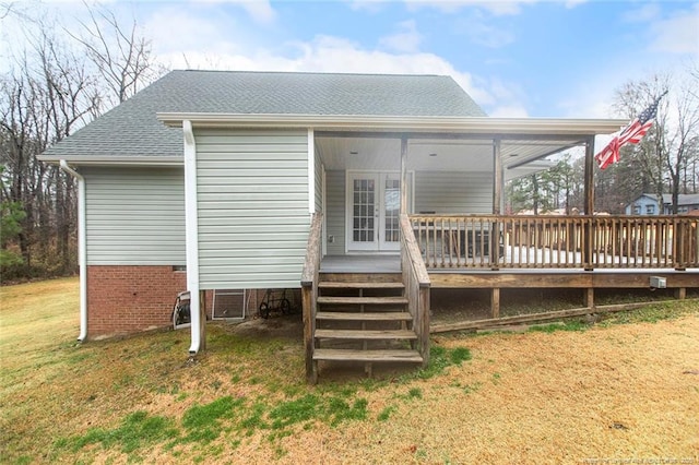 rear view of house with a wooden deck and a lawn