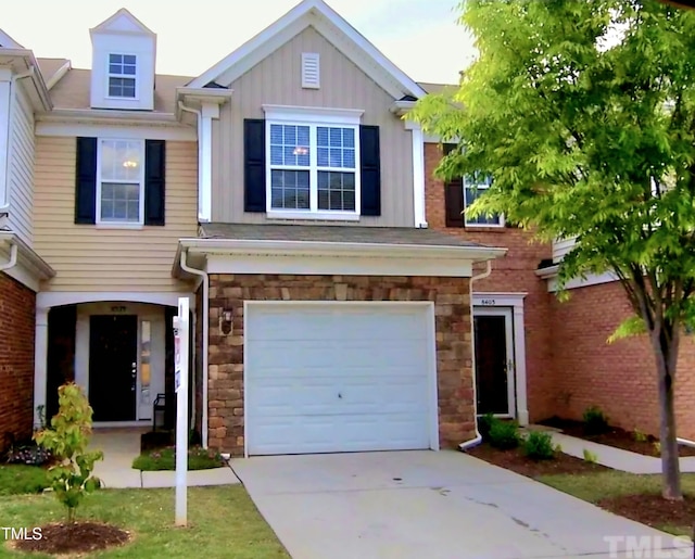 view of front of home with board and batten siding, an attached garage, stone siding, and driveway