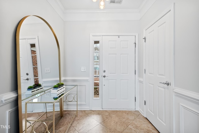 entryway with light tile patterned floors, visible vents, a decorative wall, and ornamental molding