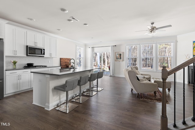 kitchen with a breakfast bar, stainless steel appliances, visible vents, decorative backsplash, and a sink