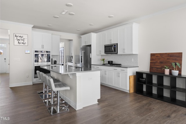 kitchen featuring a breakfast bar, crown molding, stainless steel appliances, backsplash, and a sink